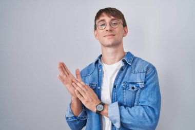 Beyaz, sarışın, gözlüklü, mutlu ve mutlu elleri alkışlayan, gururla gülümseyen bir adam. 