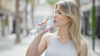 Sokakta su içen genç sarışın kadın.