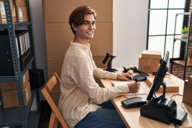 Young caucasian man ecommerce business worker writing on notebook at office
