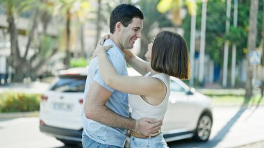 Güzel bir çift sokakta birbirlerine sarılıyor ve gülümsüyor.