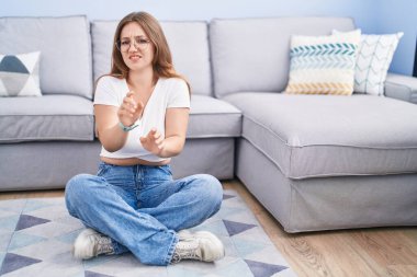 Oturma odasında yerde oturan beyaz bir kadın tiksinmiş bir ifadeyle, tiksinti ve korku dolu bir ifadeyle, tiksinti reaksiyonu yüzünden,. 