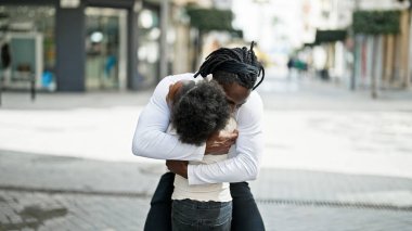 Afro-Amerikan baba ve kızı gülümsüyor sokakta birbirlerine sarılıyorlar.