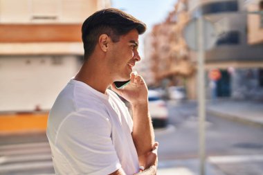 Genç İspanyol adam gülümsüyor. Kendine güveniyor. Sokakta akıllı telefondan konuşuyor.