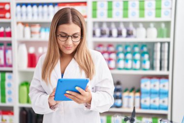 Eczanede çalışan dokunmatik ped kullanan genç, güzel İspanyol kadın eczacı.