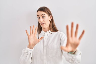 Kafkas kökenli genç bir kadın korku ifadesinden korkmuş ve dehşete düşmüş bir şekilde ayakta duruyor. El hareketlerini durdur, şok içinde bağır. panik konsepti. 