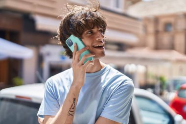 Genç sarışın adam gülümsüyor. Kendine güveniyor. Akıllı telefondan konuşuyor.