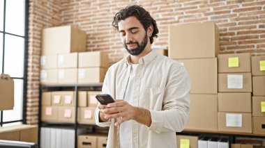 Genç bir İspanyol iş adamı ofiste kutlama yapmak için akıllı telefon kullanıyor.