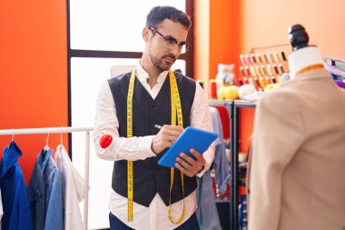 Genç İspanyol terzi atölyede dokunmatik bir ceket çiziyor.