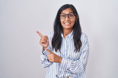 Gözlüklü genç İspanyol kadın iki eliyle endişeli ve gergin, endişeli ve şaşırmış ifadesini işaret ediyor. 