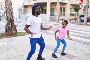 Father and daughter smiling confident dancing together at street