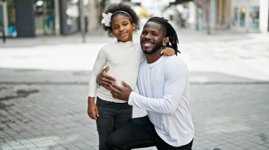 Afro-Amerikan baba ve kızı gülümsüyor sokakta birbirlerine sarılıyorlar.