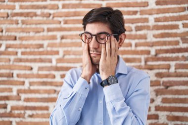 Duvarın arkasında duran Latin asıllı genç adam. Ağlarken suratını ellerle kapatan üzgün bir yüz ifadesi var. depresyon kavramı. 