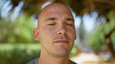 Ciddi bir ifadeyle duran ve parka gözlerini kapatmış genç bir İspanyol.