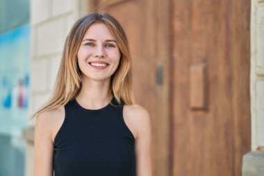 Sokakta kendine güvenen genç sarışın kadın gülümsüyor