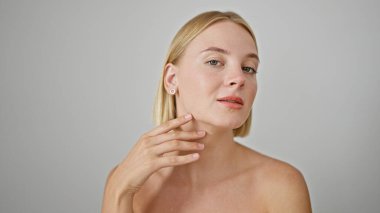 Genç sarışın kadın, izole edilmiş beyaz arka planda yüzüne dokunuyor.