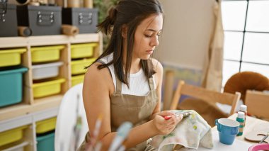 Sanat atölyesinde fırça temizleyen genç, güzel İspanyol bir sanatçı.