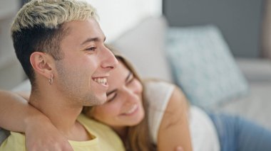 Güzel bir çift evdeki kanepede oturup birbirlerine sarılıyorlar.