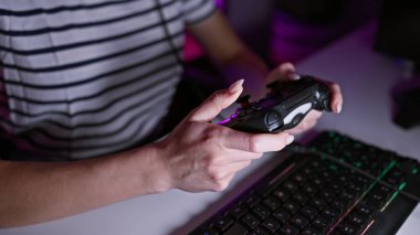 Kadın oyuncunun elleri iş başında, kadın flamalı video oyunu oynuyor oyun odasında joystick kullanıyor, gecenin sessizliğinde akış yapıyor.