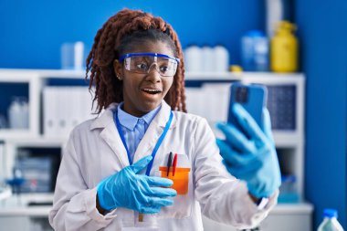 Bilim adamlarının laboratuvarında çalışan Afrikalı kadın korku ve şaşkınlık dolu, ağzı açık, inançsız bir yüz ifadesiyle video çekiyor. 