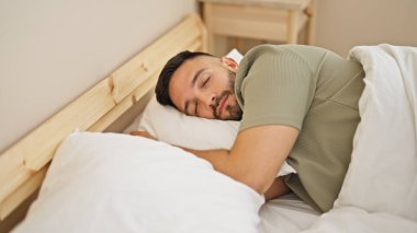 Genç İspanyol adam yatakta uzanıp yatak odasında uyuyor.