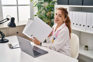 Klinikte dizüstü bilgisayar okuyan genç bir kadın.