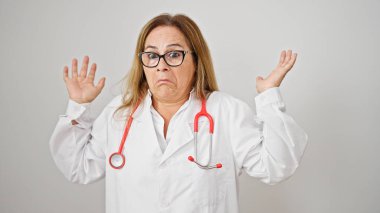 Orta yaşlı İspanyol kadın doktor soyutlanmış beyaz arka planda hiçbir şeyden habersiz duruyor.