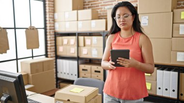 Young chinese woman ecommerce business worker using touchpad at office