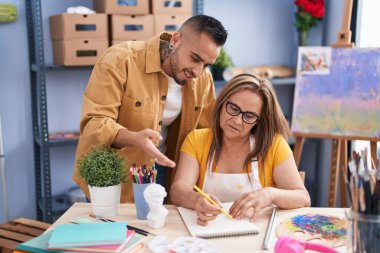 Man and woman artists smiling confident drawing on notebook at art studio