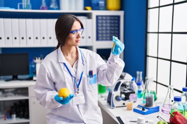 Laboratuvarda limon ve test tüpü tutan genç ve güzel İspanyol bilim kadını.