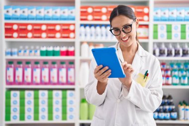 Eczanede çalışan dokunmatik ped kullanan genç, güzel İspanyol kadın eczacı.