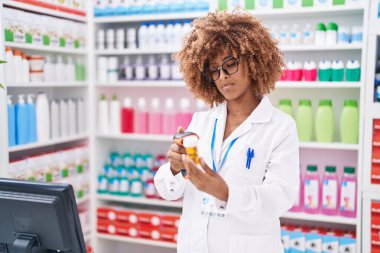 Afrikalı Amerikalı kadın eczacı eczanede ilaç şişesini tarıyor.
