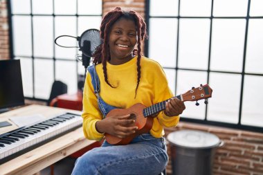 Müzik stüdyosunda ukulele çalan Afrikalı Amerikalı kadın müzisyen.