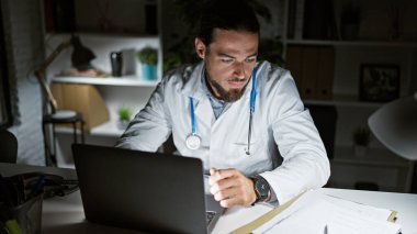 Genç İspanyol doktor klinikte çalışırken dizüstü bilgisayar kullanıyor.