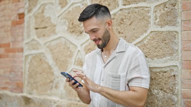 Genç İspanyol adam akıllı telefon kullanıyor. Sokakta ciddi bir ifadesi var.