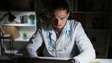 Genç İspanyol doktor klinikte çalışırken dizüstü bilgisayar kullanıyor.