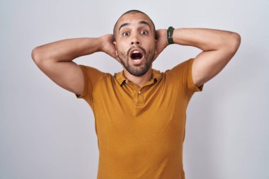 Beyaz arka planda duran İspanyol sakallı adam çıldırmış ve elleri başının üstünde korkmuş, korkmuş ve ağzı açık şoktan şaşırmış. 