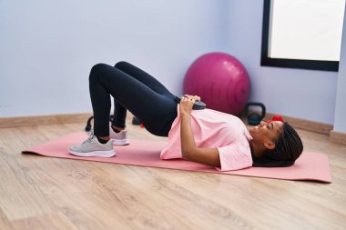 Afrikalı Amerikalı kadın gülümsüyor spor merkezinde kendine güvenen karın kasları egzersizi yapıyor