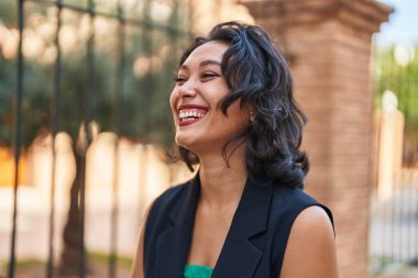 Young beautiful hispanic woman smiling confident looking to the side at street
