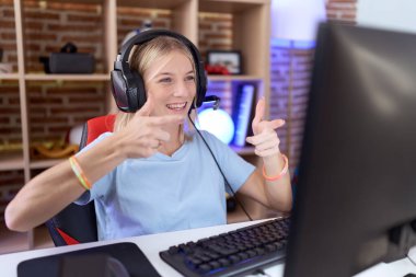 Video oyunları oynayan, kulaklık takan, mutlu ve komik yüzlü genç beyaz bir kadın. iyi enerji ve titreşimler. 