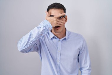 İş kıyafetleri ve gözlük takan yakışıklı İspanyol adam. Şoka girip yüzünü ve gözlerini kapayarak utangaç ifadesiyle parmaklarının arasından bakıyor.. 