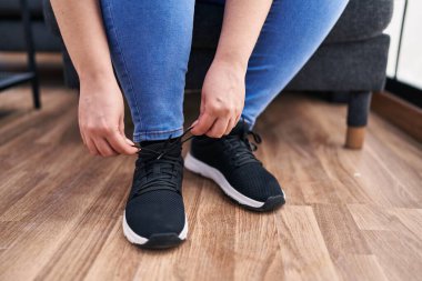 Evde ayakkabı bağlayan genç ve güzel bir kadın.