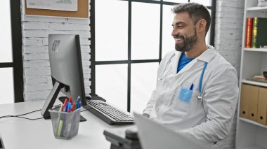 Yakışıklı genç İspanyol bir adam, kendine güvenen bir doktor, hareketli klinikte bilgisayarında çalışmaktan mutlu, profesyonel ve çalışkan, sağlık hizmetleri rolünde..