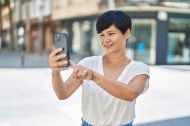 Middle age chinese woman smiling confident making selfie by the smartphone at street