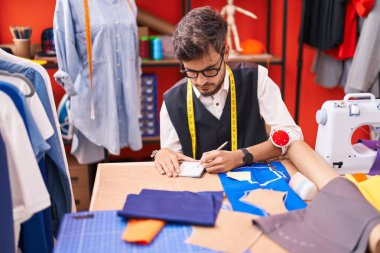 Genç İspanyol terzi atölyedeki deftere yazı yazıyor.