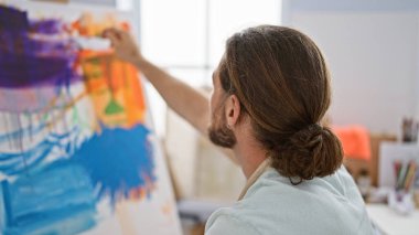 Sanat stüdyosunda resim çizen genç bir İspanyol.
