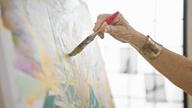 Sanat stüdyosundaki kadın ressamın elleri zarifçe tuvale resim çiziyor. Yerel akademideki olgun öğrenciler için yaratıcılık dersi.