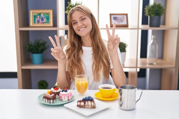 Młoda Biała Kobieta Jedząca Ciastka Śniadanie Uśmiechnięta Kamery Pokazująca Palce — Zdjęcie stockowe