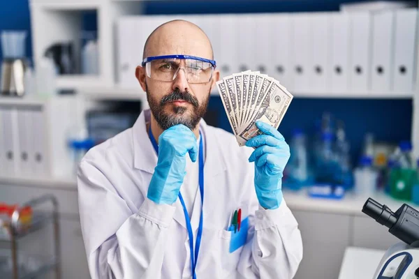 Young Hispanic Man Working Scientist Laboratory Holding Money Serious Face — Photo