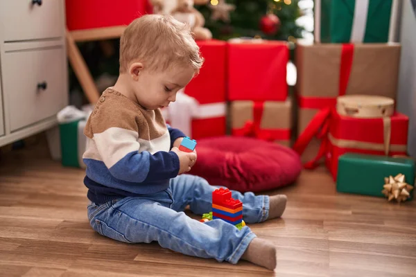 愛らしい幼児遊びます建設ブロックで床に座っていますクリスマスプレゼントによって家 — ストック写真