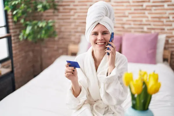 Junge Blonde Frau Bademantel Spricht Auf Smartphone Und Hält Kreditkarte — Stockfoto